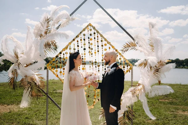 Düğün töreninde kemerin yanında mutlu bir çift var..