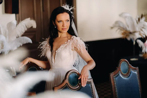 Masalarda tüylerle süslenmiş bir restoranın içinde gelinlik giymiş şık bir gelin..