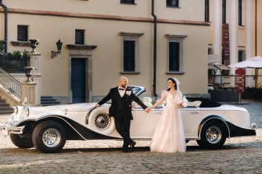 Şatonun avlusunda, eski bir arabanın yanında zarif bir çift..