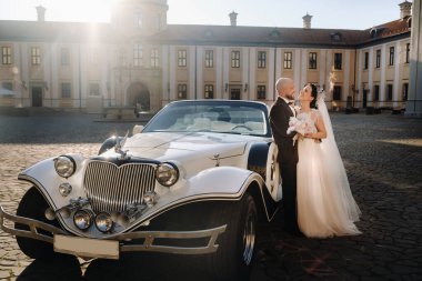 Şatonun avlusunda, eski bir arabanın yanında zarif bir çift..