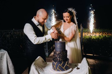 Şık gelin ve damat, akşam sokakta düğün pastasını kestiler..