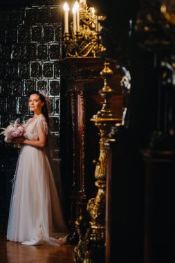 Gelinlik giymiş gelin ve elinde buket kalenin eski iç kısmında duruyor..