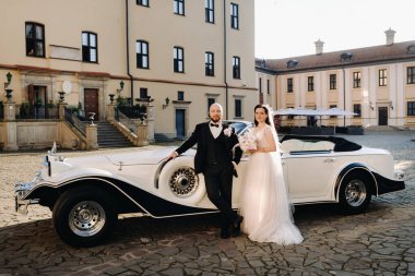 Şatonun avlusunda, eski bir arabanın yanında zarif bir çift..