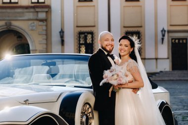 Şatonun avlusunda, eski bir arabanın yanında zarif bir çift..