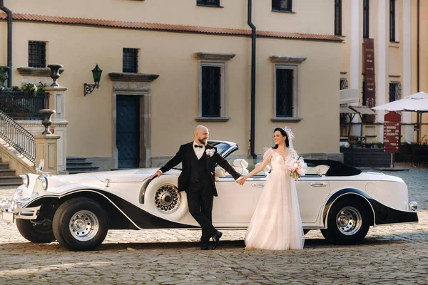 Şatonun avlusunda, eski bir arabanın yanında zarif bir çift..