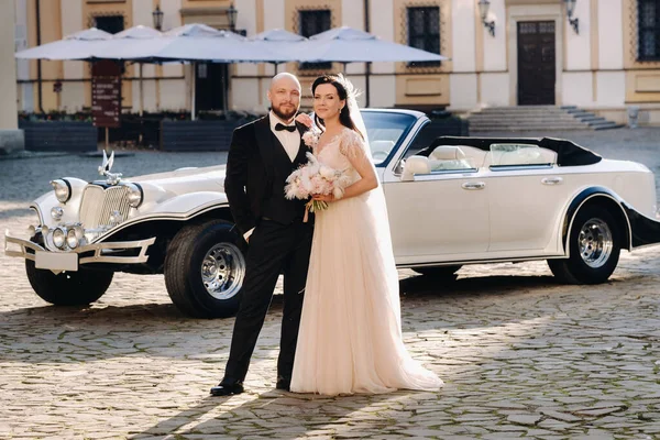 Şatonun avlusunda, eski bir arabanın yanında zarif bir çift..