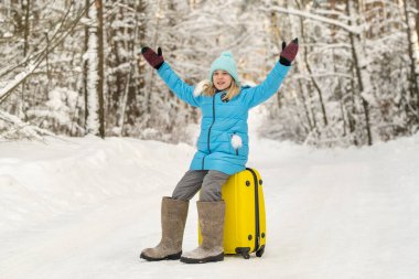 Kışın keçeli çizmeli bir kız dondurucu karlı bir günde bavulda oturur..