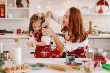Anne ve kızı yeni yıl mutfağında birlikte Noel kurabiyeleri için hamur hazırlıyorlar..