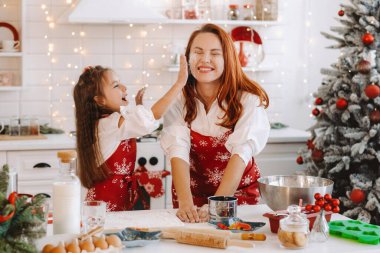 Anne ve kızı yeni yıl mutfağında birlikte Noel kurabiyeleri için hamur hazırlıyorlar..