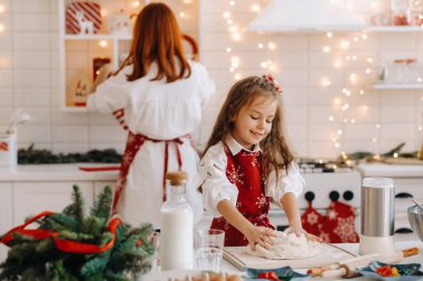 Anne ve kızı yeni yıl mutfağında birlikte Noel kurabiyeleri için hamur hazırlıyorlar..