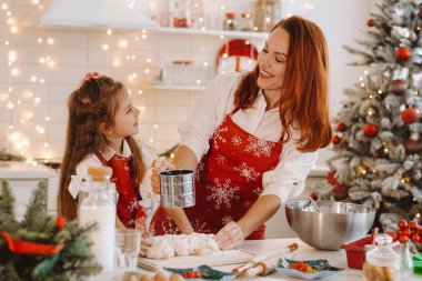 Anne ve kızı yeni yıl mutfağında birlikte Noel kurabiyeleri için hamur hazırlıyorlar..