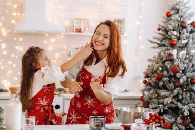 Anne ve kızı yeni yıl mutfağında birlikte Noel kurabiyeleri için hamur hazırlıyorlar..