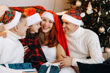 Mutlu bir ailenin yakın plan portresi bir Noel ağacının yanındaki koltukta oturuyor ve bayramı kutluyor.