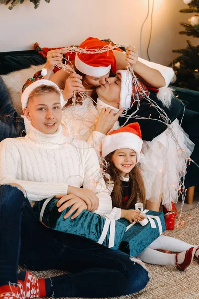 Retrato de cerca de una familia feliz sentada en un sofá cerca de un árbol de Navidad celebrando unas vacaciones —  Fotos de Stock