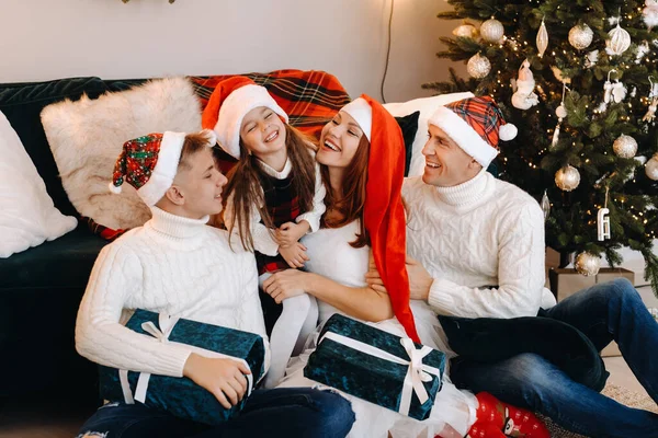 Close-up portrait of a happy family sitting on a sofa near a Christmas tree celebrating a holiday — Stock Photo, Image