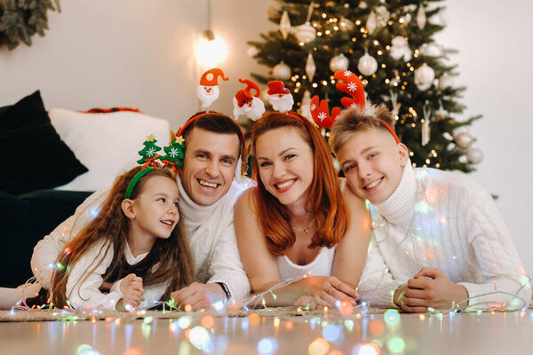 Close-up portrait of a happy family lying near a Christmas tree celebrating a holiday.