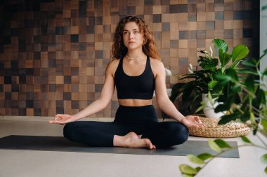 Siyah elbiseli genç bir kadın modern bir spor salonunda yoga yapıyor. Sağlık konsepti..