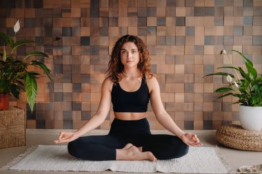 Siyah elbiseli genç bir kadın modern bir spor salonunda yoga yapıyor. Sağlık konsepti..