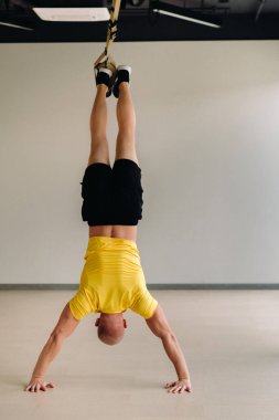 Odaklanmış bir erkek sporcu spor salonunda fonksiyonel döngüler üzerinde bir egzersiz yapıyor..