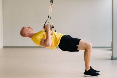 Odaklanmış bir erkek sporcu spor salonunda fonksiyonel döngüler üzerinde bir egzersiz yapıyor..