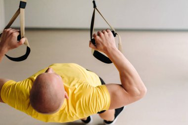 Odaklanmış bir erkek sporcu spor salonunda fonksiyonel döngüler üzerinde bir egzersiz yapıyor..