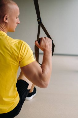 Odaklanmış bir erkek sporcu spor salonunda fonksiyonel döngüler üzerinde bir egzersiz yapıyor..