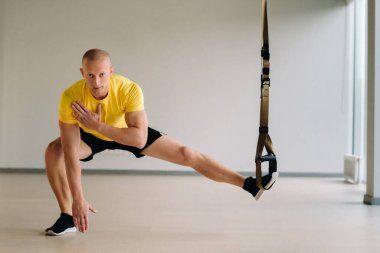 Odaklanmış bir erkek sporcu spor salonunda fonksiyonel döngüler üzerinde bir egzersiz yapıyor..