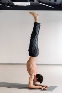 Spor salonunda elleri üzerinde duran, kemikli gövdeli bir adam..