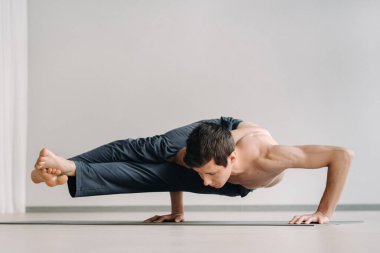 Kemikli gövdeli bir adam spor salonunda amuda kalkarken eğiliyor..