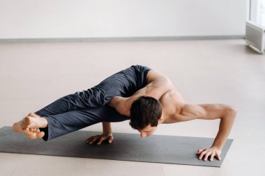 Kemikli gövdeli bir adam spor salonunda amuda kalkarken eğiliyor..