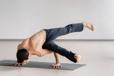 Kemikli gövdeli bir adam spor salonunda amuda kalkarken eğiliyor..