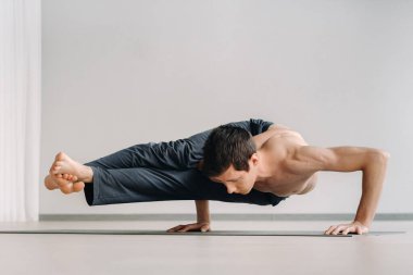 Kemikli gövdeli bir adam spor salonunda amuda kalkarken eğiliyor..