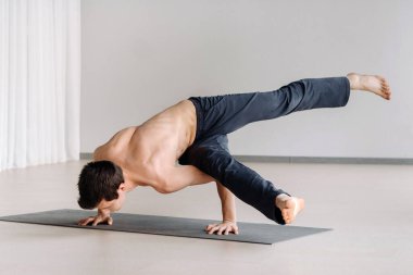 Kemikli gövdeli bir adam spor salonunda amuda kalkarken eğiliyor..