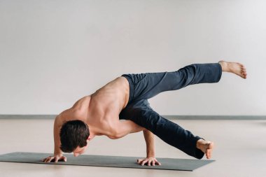 Kemikli gövdeli bir adam spor salonunda amuda kalkarken eğiliyor..