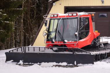 Kış mevsiminde ahırın yakınındaki ormanda duran kırmızı raylarda bir kar küreme aracı.,