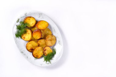 Beyaz arka planda dereotlu beyaz bir tabakta kızarmış patates dilimleri..