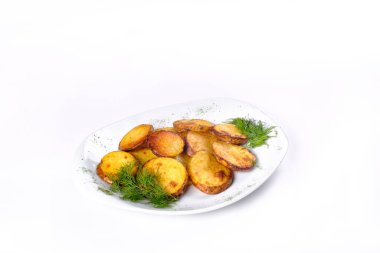 Beyaz arka planda dereotlu beyaz bir tabakta kızarmış patates dilimleri..