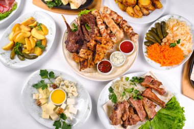 Bir sürü farklı yemek tabağı olan örtülü bir masa. İzole edilmiş beyaz bir arka planda bir sürü yiyecek..