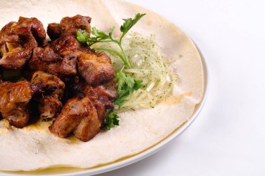Lavaşlı domuz şiş kebap beyaz bir tabakta beyaz izole bir zemin üzerinde yatıyor..