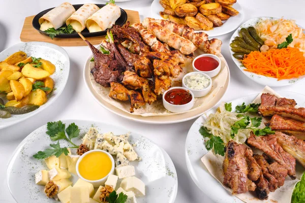 Bir sürü farklı yemek tabağı olan örtülü bir masa. İzole edilmiş beyaz bir arka planda bir sürü yiyecek..