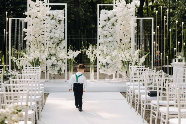 A place for a wedding ceremony on the street and a boy walking along the path. Decorated wedding venue.