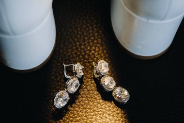 Düğün günü. Evlilik küpeleri masanın üstünde. Gelinin sabahı, mücevher aksesuarları.