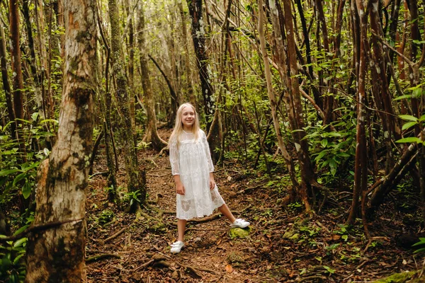 白いドレスの少女が熱帯の島のジャングルを歩く — ストック写真