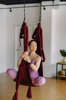 Kız sallanan bir hamakta oturuyor ve spor salonunda yoga yapıyor..