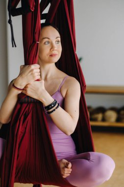 Kız sallanan bir hamakta oturuyor ve spor salonunda yoga yapıyor..