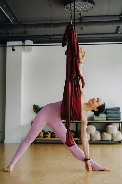 Una Mujer Ropa Rosa Hace Yoga Una Hamaca Borgoña Suspendida — Foto de Stock
