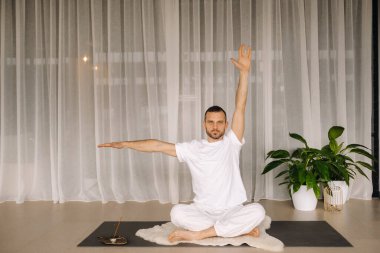 Beyaz spor giyimli bir adam spor salonunda yoga yapıyor. Sağlıklı yaşam tarzı kavramı.