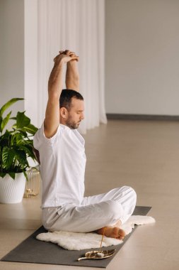 Beyaz spor giyimli bir adam spor salonunda yoga yapıyor. Sağlıklı yaşam tarzı kavramı.
