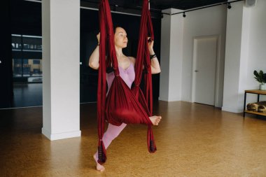 Kız havadan yoga yapıyor, spor salonundaki hamakta esneme egzersizleri yapıyor..