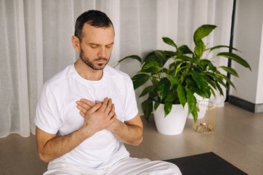 Beyaz spor giyimli bir adam spor salonunda yoga yapıyor. Sağlıklı yaşam tarzı kavramı.